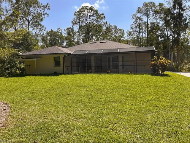 Back of house featuring a lanai, a lawn, a sunroom, and stucco siding