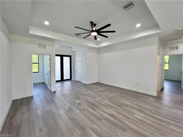 Unfurnished room with french doors, wood-type flooring, a tray ceiling, and ceiling fan