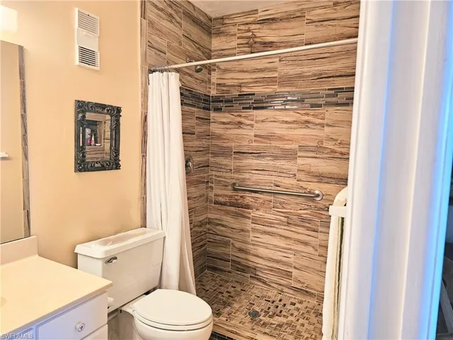 Bathroom featuring vanity, walk in shower, and toilet