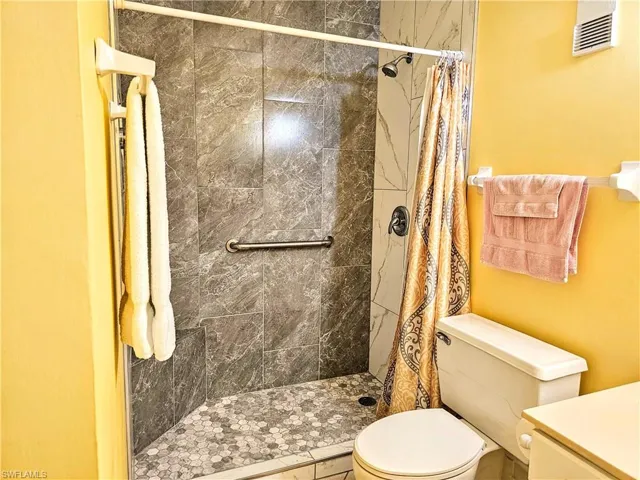 Bathroom featuring toilet, vanity, and a shower with shower curtain