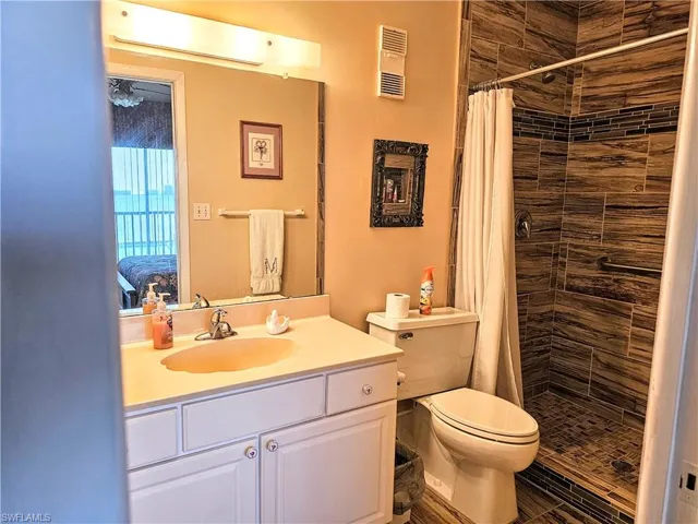 Bathroom with curtained shower, vanity, and toilet