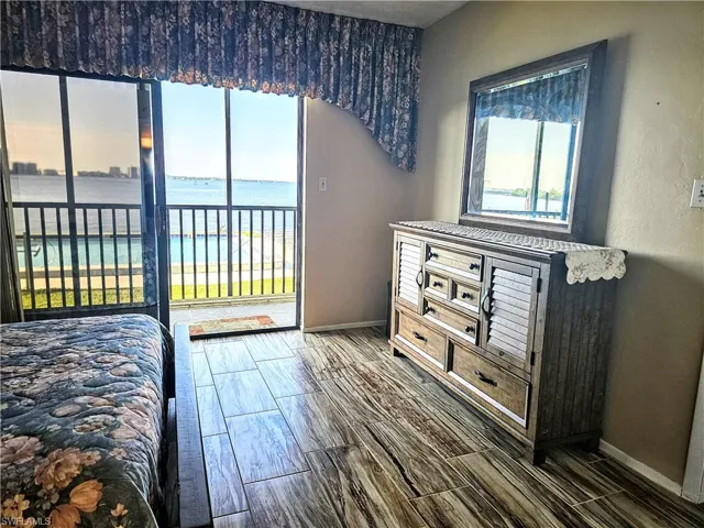 Bedroom with a water view and dark hardwood / wood-style floors