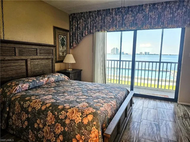 Bedroom with hardwood / wood-style floors, a water view, and access to outside