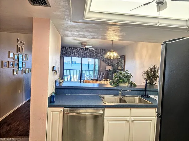 Kitchen featuring sink, white cabinetry, appliances with stainless steel finishes, wood-type flooring, and ceiling fan