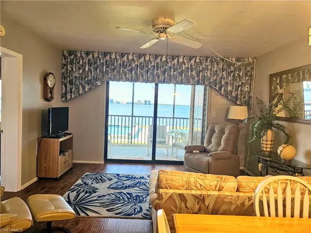 Living room with ceiling fan, dark hardwood / wood-style flooring, and a healthy amount of sunlight