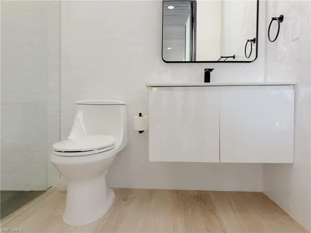 Bathroom with toilet, tile walls, and vanity