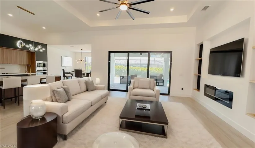 Living area featuring a wealth of natural light, visible vents, light wood finished floors, and a raised ceiling