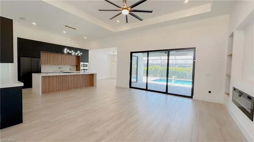 Kitchen featuring modern cabinets, a sink, a tray ceiling, open floor plan, and light countertops