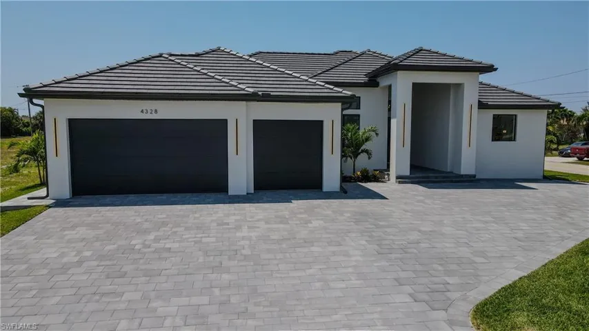 View of front of house featuring a tiled roof, a garage, driveway, and stucco siding