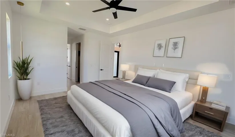 Bedroom with a ceiling fan, wood finished floors, baseboards, a tray ceiling, and recessed lighting