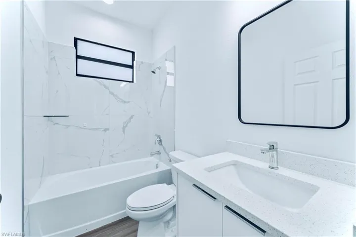 Full bathroom featuring vanity, toilet, wood-type flooring, and tiled shower / bath combo
