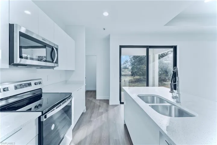 Kitchen featuring white cabinetry, sink, light stone countertops, and appliances with stainless steel finishes