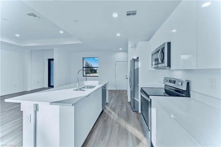 Kitchen featuring white cabinets, a raised ceiling, sink, appliances with stainless steel finishes, and light hardwood / wood-style floors