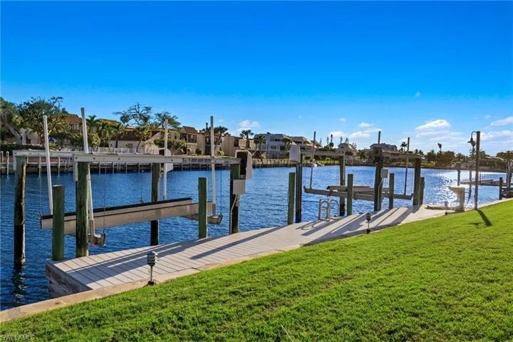 Dock with a yard, a water view, a residential view, and boat lift