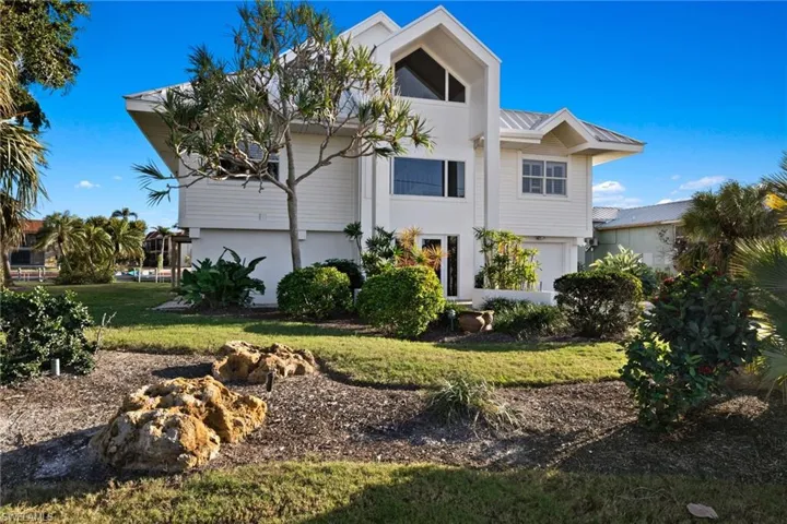 View of front of home featuring a metal roof, a front yard, and stucco siding