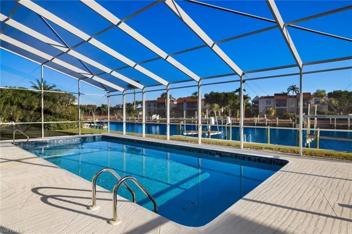 Swimming pool with a lanai, a water view, a sunroom, and a boat dock