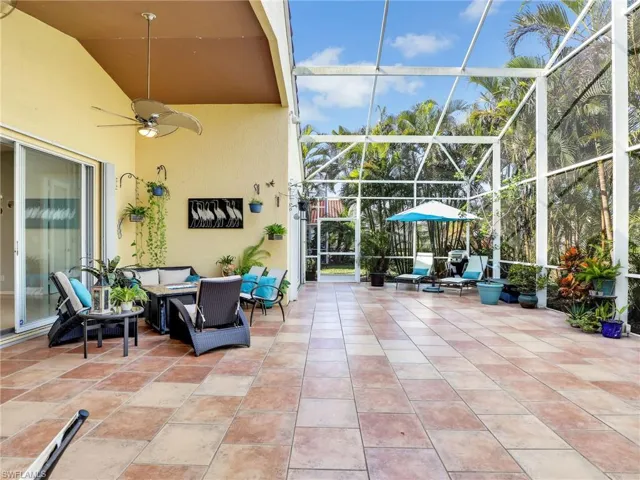 View of patio with an outdoor hangout area, glass enclosure, and ceiling fan