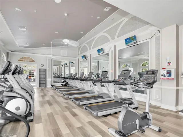 Workout area featuring ceiling fan, light hardwood / wood-style floors, and lofted ceiling