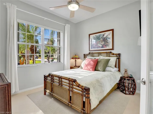 Tiled bedroom featuring multiple windows and ceiling fan