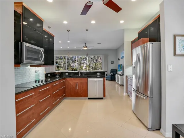 Kitchen with pendant lighting, backsplash, dark stone counters, sink, and stainless steel appliances