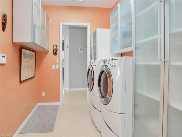 Washroom with washer and clothes dryer, cabinets, and light tile patterned floors