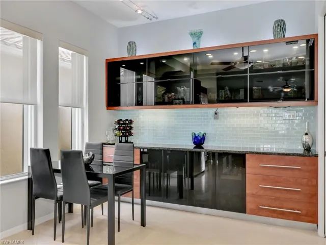 Bar with light tile patterned floors, backsplash, rail lighting, and dark stone countertops