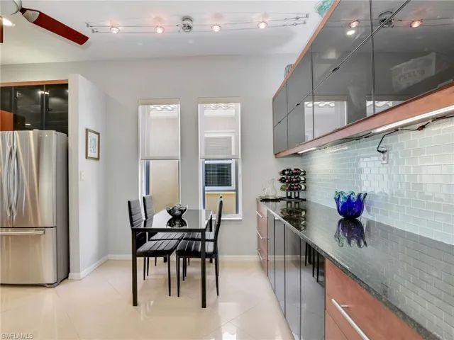 Kitchen featuring stainless steel refrigerator, ceiling fan, tasteful backsplash, dark stone counters, and light tile patterned flooring
