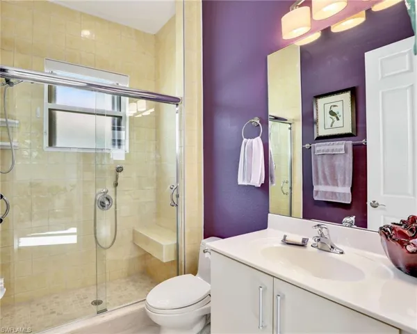 Bathroom featuring vanity, toilet, and a shower with door