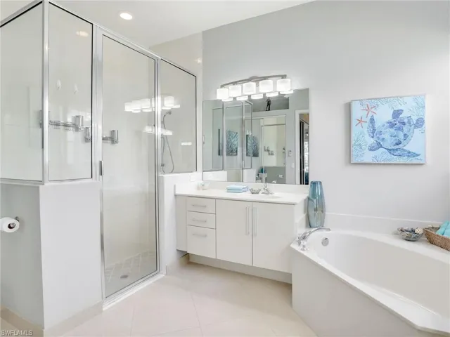 Bathroom with separate shower and tub, tile patterned flooring, and vanity