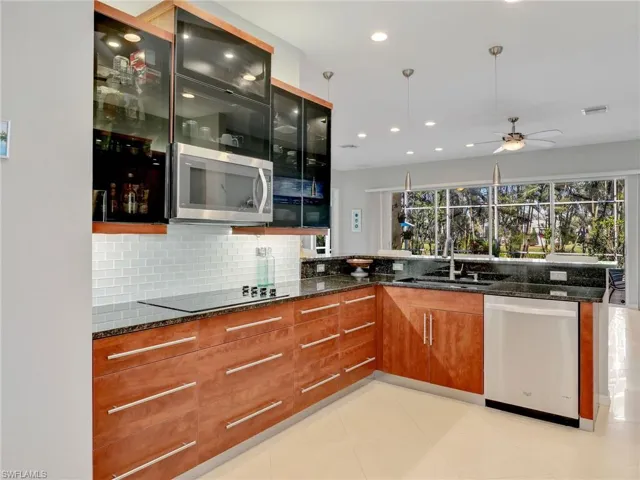 Kitchen with dark stone counters, ceiling fan, sink, and stainless steel appliances
