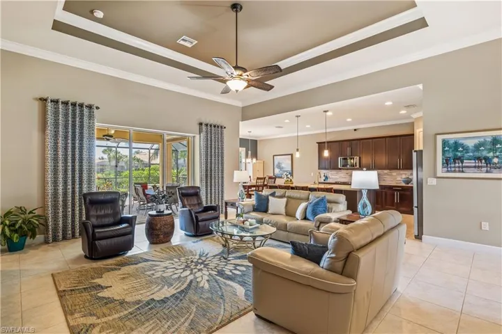 Large Great Room featuring crown molding,  tray ceiling, and large tile throughout