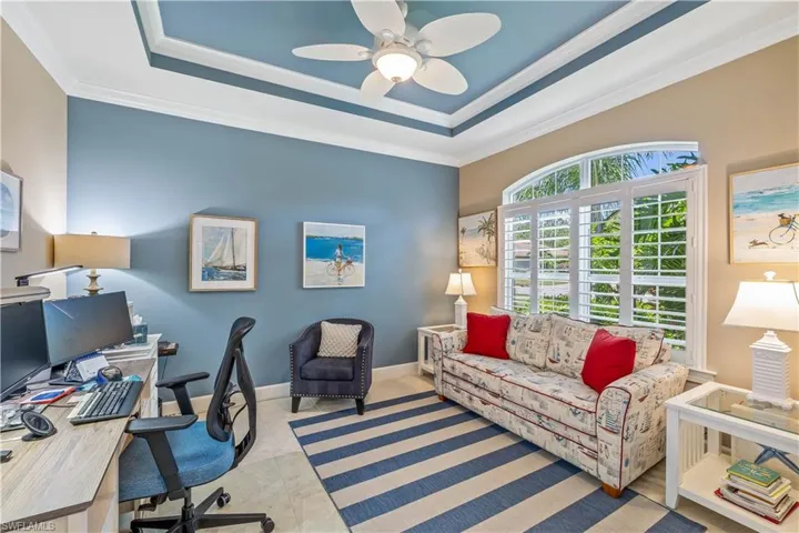 Home office with crown molding, light tile floors, and a tray ceiling