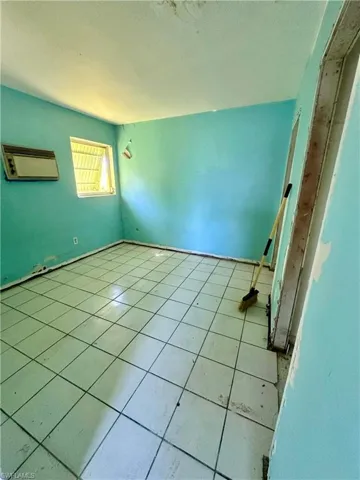 Unfurnished bedroom featuring tile patterned floors, a textured ceiling, and a wall mounted AC