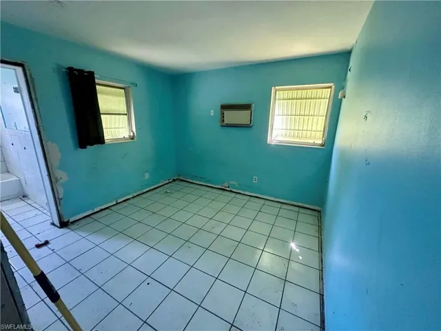 Empty room with light tile patterned floors and a wall mounted air conditioner