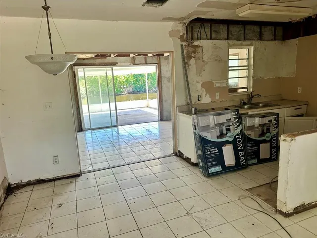 Kitchen with light countertops, white cabinets, decorative light fixtures, and light tile patterned floors