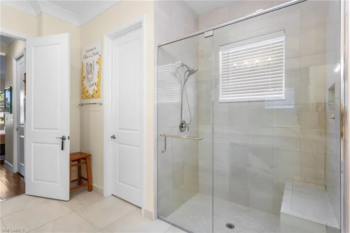 Bathroom featuring a stall shower, light tile patterned flooring, ensuite bathroom, and crown molding