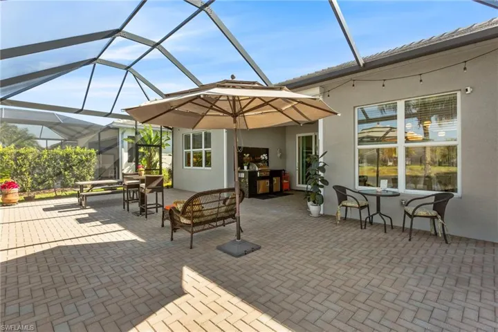 View of patio with glass enclosure, a sunroom, and outdoor dining area