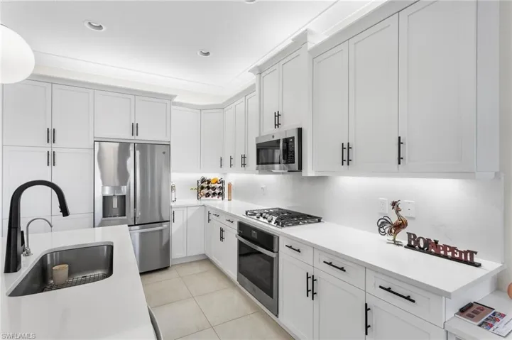 Kitchen with stainless steel appliances, white cabinets, light stone counters, light tile patterned floors, and recessed lighting