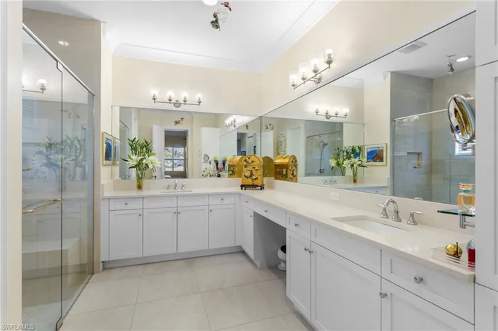 Full bathroom featuring a shower stall, double vanity, crown molding, and light tile patterned floors