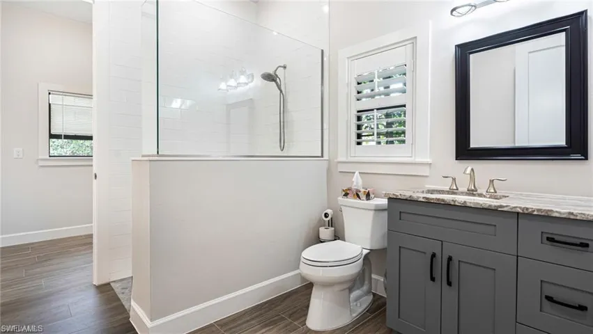 Bathroom with toilet, tile walk-in shower, and vanity