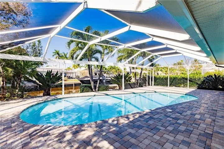 Swimming pool featuring glass enclosure, a patio, and a sunroom