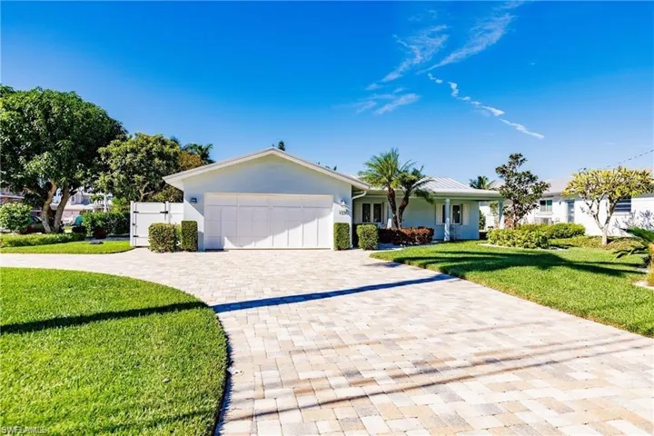 Ranch-style house featuring a front lawn, decorative driveway, a garage, and stucco siding