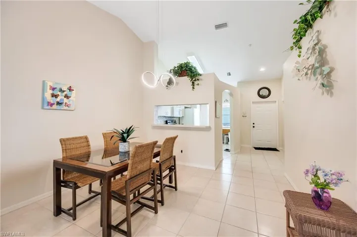 Dining area with arched walkways, light tile patterned flooring, and lofted ceiling