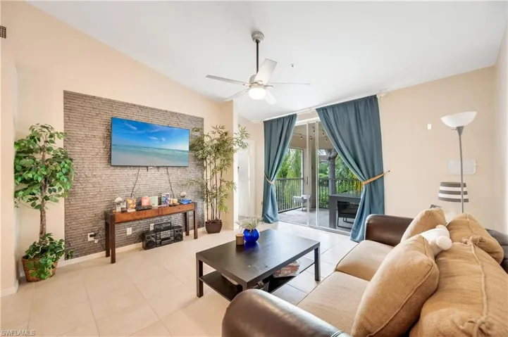 Tiled living area featuring vaulted ceiling and ceiling fan