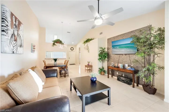 Living area with light tile patterned floors, a ceiling fan, and high vaulted ceiling