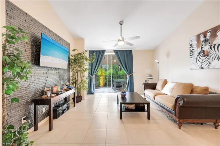 Tiled living area with a ceiling fan, brick wall, and an accent wall