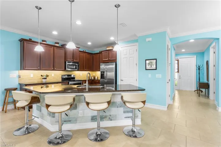 Kitchen with a breakfast bar, dark stone counters, ornamental molding, stainless steel appliances, and recessed lighting