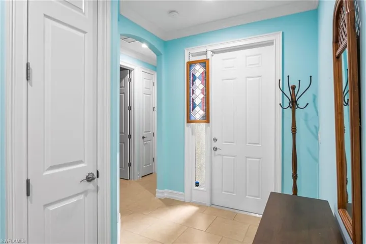 Foyer featuring arched walkways, crown molding, and light tile patterned flooring