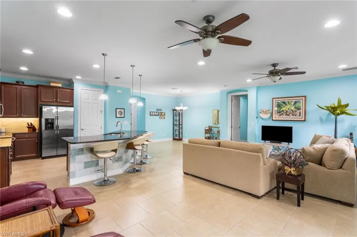 Living area with a ceiling fan, recessed lighting, crown molding, light tile patterned floors, and a chandelier