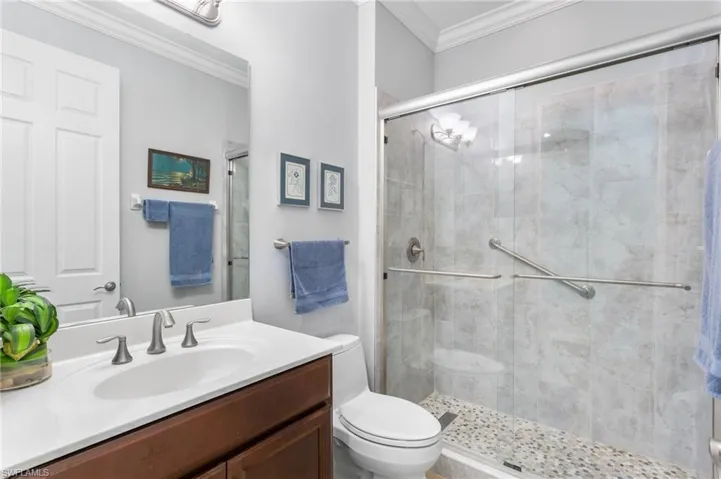 Bathroom with vanity, ornamental molding, and a shower stall
